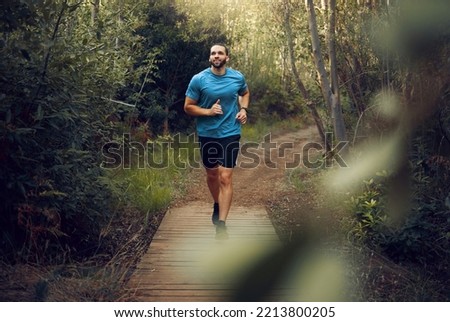 Man, running and fitness on forest path, nature woods bridge or countryside environment for health, wellness or heart health. Smile, happy or sports runner in exercise, training and workout in Canada