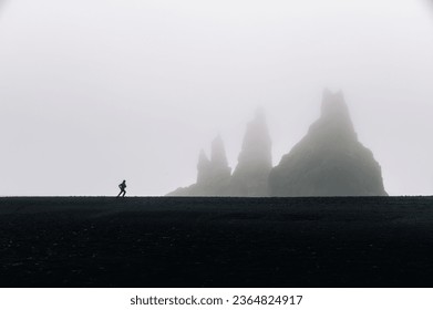 A man running and misty hills and mountains in the background. A runner is jogging in the wild nature of Iceland. A sportsman is exercising in stormy weather.