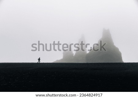 A man running and misty hills and mountains in the background. A runner is jogging in the wild nature of Iceland. A sportsman is exercising in stormy weather.