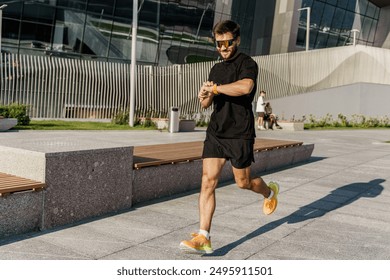 A man running in a modern urban area, checking his smartwatch, wearing athletic gear and sunglasses.

 - Powered by Shutterstock