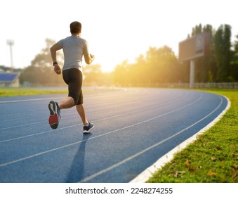 A man running on athletic track with sunrise background.

 - Powered by Shutterstock