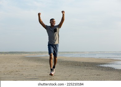 Man running on beach with arms outstretched celebrating
