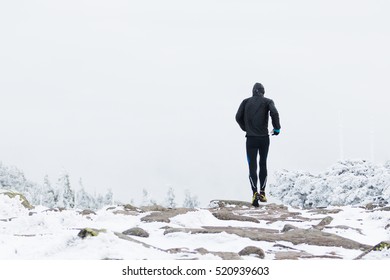 Man Running On The Cold Mountain Trail In Winter With Snow