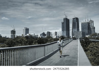 A man running up on footbridge in the city center park for cardio workout.  Health and Lifestyle in big city life concept. - Powered by Shutterstock