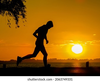 Man Running On Lake Shore During Sunset