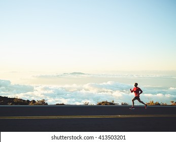 Man running on mountain road at sunset