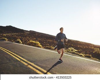 Man running on mountain road in golden afternoon light