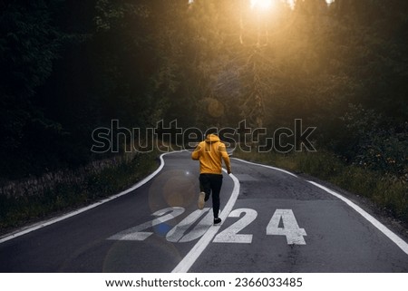  Man running on the mountain road towards new goals in 2024. New Year 2024 with new ambitions, challenge, plans, goals and visions.