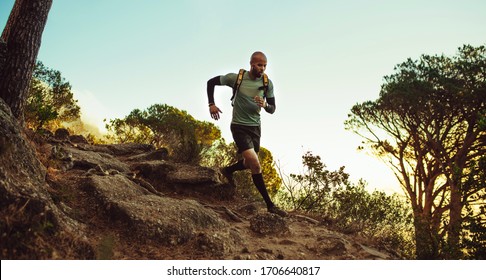 Man running on mountain trail. Fitness male running through rocky mountain path.