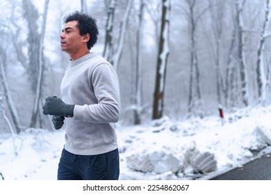 Man running on a trail in the woods on a winter morning, he's training for a marathon - Shutterstock ID 2254862067