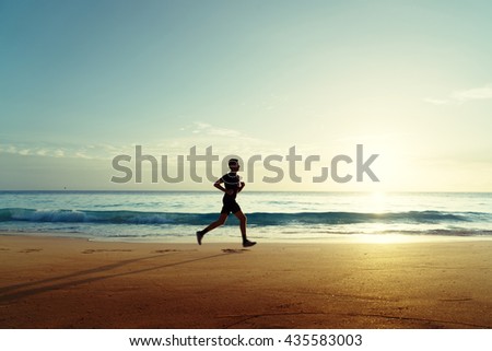 Man running on tropical beach at sunset
