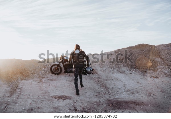 Man running to ride a\
motorcycle.