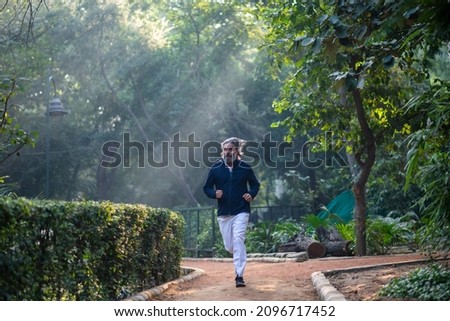 Man Running in a sun bursting park, Fit senior male jogger exercising in the park in early morning.