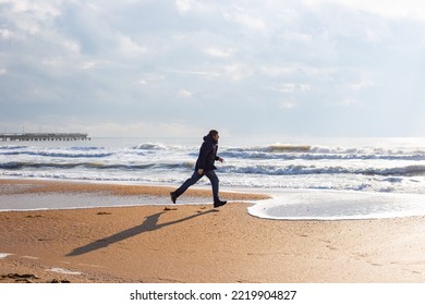 A man runs along the sea sandy shore on a sunny winter day. Travel and tourism. - Shutterstock ID 2219904827