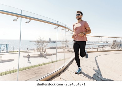 A Man Runs Along the Waterfront Promenade on a Sunny Day, Enjoying the Fresh Air and Scenic Views of the Sea - Powered by Shutterstock