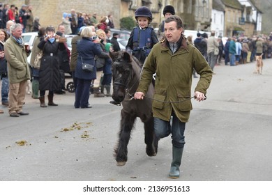 A Man Runs With A Child On A Pony During The Traditional Boxing Day Hunt On December 26, 2013 In Chippenham, UK. Fox Hunting Is Technically Outlawed In The UK With Meets Following Scented Trails.