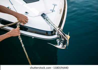 Man s hand with boat rope. Yachtsman moors his motor boat at jetty. Close up hands and bow of the boat.