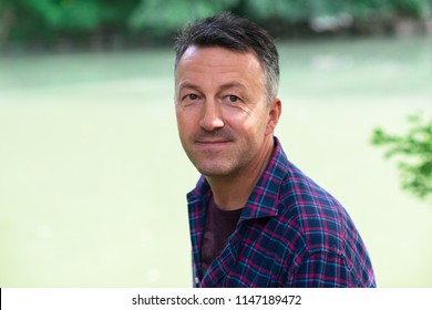 Man' S Outdoor Portrait. Handsome Mature Man Lokking At Camera And Smiling Over Nature Background.