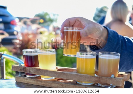 Man sampling a variety of seasonal craft beer at an outdoor beer garden, hands only