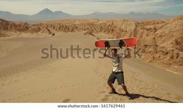 Man with sand board at a dune in the\
Atacama desert near San Pedro de Atacama,\
Chile.