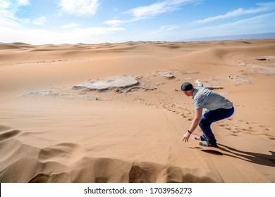 Man Sand Boarding On Sahara Desert Down The Dune, Africa 