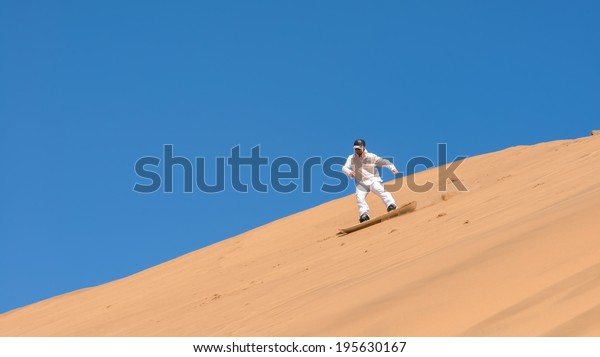 Man sandboarding in\
Namibia, Africa