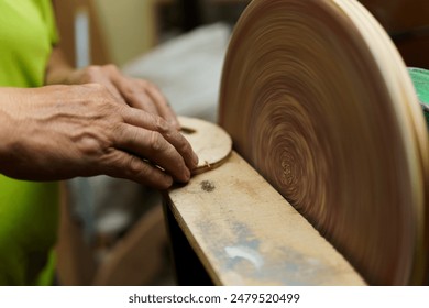 A man is sanding a piece of wood with a hand. The wood is being sanded with a sanding machine - Powered by Shutterstock