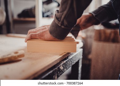 Man sanding wooden panel. Process of manual sanding of a furniture part. Process of manual sanding of furniture stock in the carpentry shop - Shutterstock ID 700387264