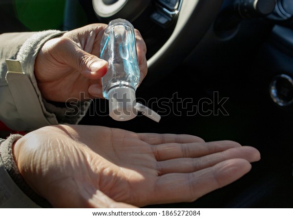 A man sanitizes his hands by using hand gel\
before driving a car to avoid the spread of coronavirus (covid-19)\
or any kind of germs. Health care prevention and protection when\
being outdoor