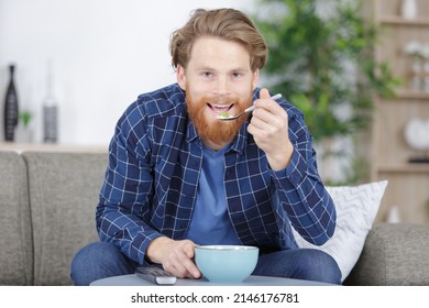 Man Sat On The Sofa Eating From A Bowl