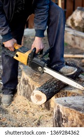 A Man Is Sawing A Log With An Electric Saw, Wood Chips Are Flying