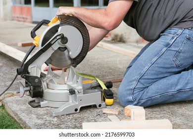A man sawing wood with a multi material construction saw on the ground.