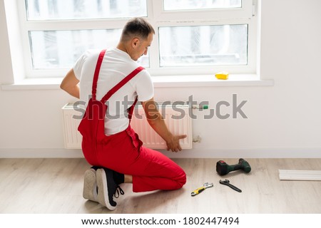 A man saws off a pipe with a circular saw, flying sparks, replacement of the radiator in the apartment, plumbing work [[stock_photo]] © 