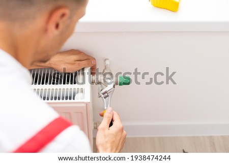 A man saws off a pipe with a circular saw, flying sparks, replacement of the radiator in the apartment, plumbing work [[stock_photo]] © 