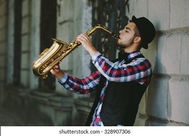 Man With Saxophone Outside Near The Brick Wall