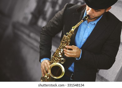 Man With Saxophone Outside Near The Brick Wall