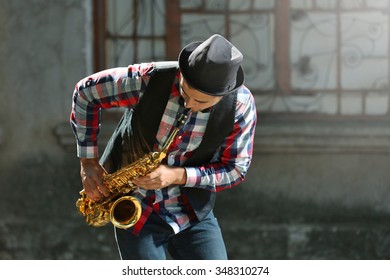 Man With Saxophone Outside Near The Brick Wall