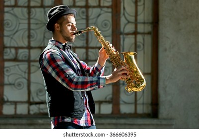 Man With Saxophone Outside Near The Brick Wall