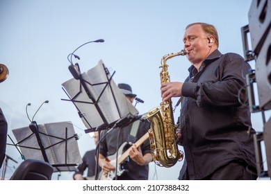 Man saxophonist playing in orchestra on the street