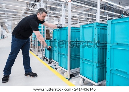Man scanning boxes on tugger train in industrial hall