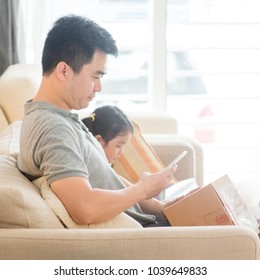 Man scanning QR code with smart phone. Asian family at home, living lifestyle indoors.
