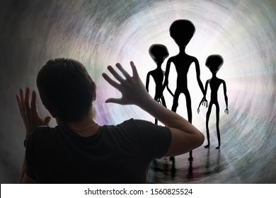 Man is scared of silhouettes of aliens in tunnel. Abduction and kidnapping by aliens concept.
