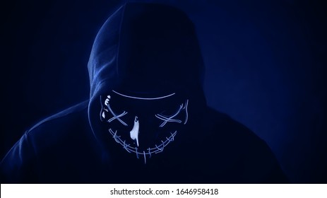 Man In Scary Lighting Neon Glow Mask In Hood In Phantom Blue Color. Halloween And Horror Concept.