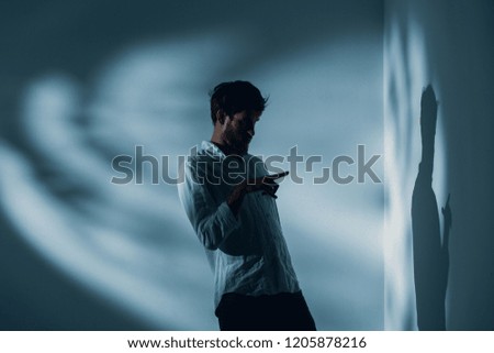 Man with schizophrenia standing alone in a room pointing at his shadow on the wall, real photo with copy space