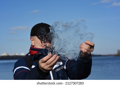 A Man Scientist Holds A Sample Of Translucent Ice Floe And Explores It. Global Warming, Melting Ice, Climate Change And Environmental Protection Concept. Ice Research. Measuring Ice Runoff