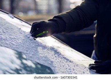 Man Scraping Ice From The Windshield Of A Car