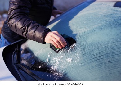 Man Scraping Ice From The Windshield Of A Car