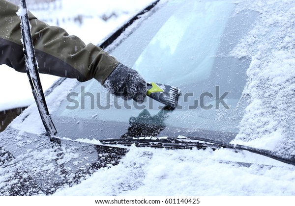man is scraping a wind
screen of a car