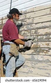 Man Scrapping Paint From House