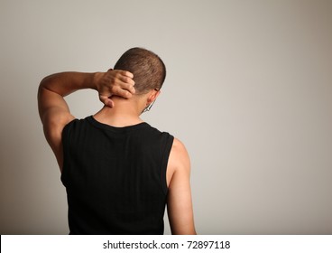 Man Scratching Back Of The Head Against Wall.